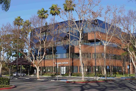 The Angeles Institute is a large, modern building with a glass facade and a brown roof.