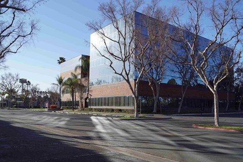 A modern building with a glass facade is surrounded by trees.