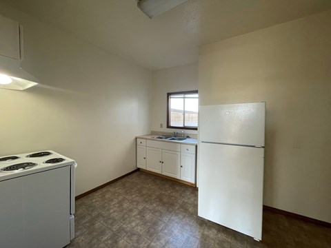 A kitchen with a white refrigerator, white stove, and white cabinets.