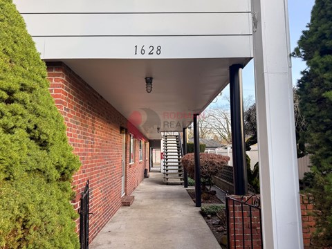A long white covered walkway with a number 1628 on the wall.