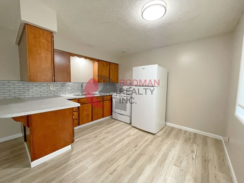 A kitchen with wooden cabinets and a Budman Realty Inc. sign.