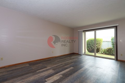 A room with a wooden floor and a window that is empty and waiting to be filled.