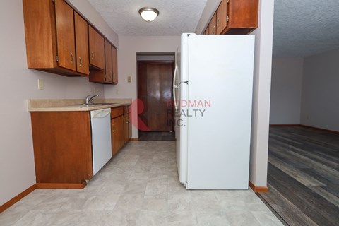 A kitchen with a white fridge and wooden cabinets.