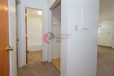 A hallway with a door on the left and a wall on the right with a sign that says "Rodman Realty Inc.".