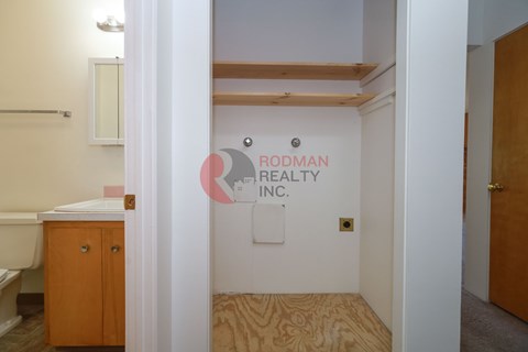 A room with a wooden floor and a sign that says Rodman Realty Inc.