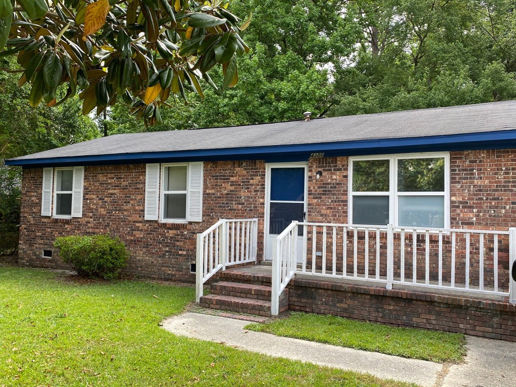 a small brick house with a porch and a blue door