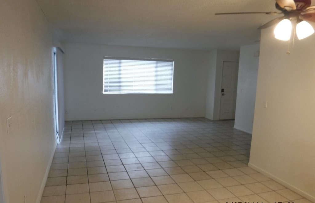 an empty living room with tiled floors and a window