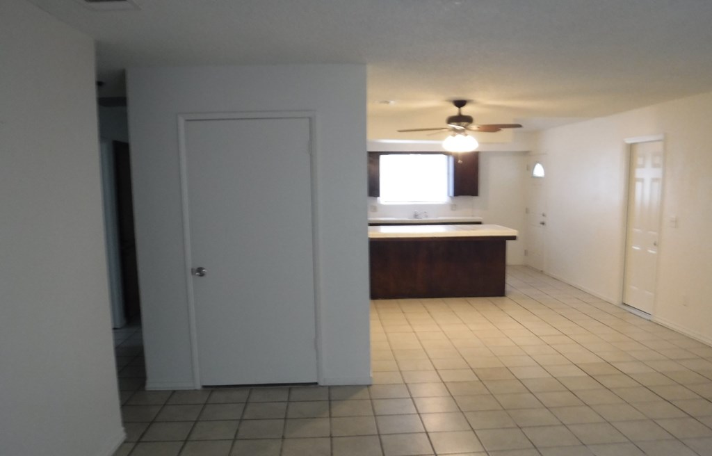 an empty kitchen with a white tile floor and a ceiling fan