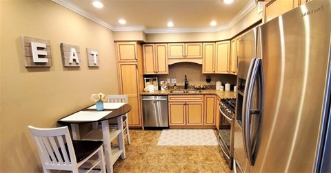A kitchen with a table and chairs and a refrigerator.