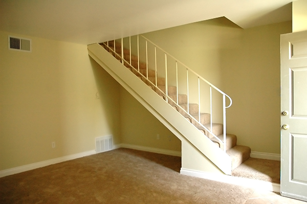 the bottom of a staircase in a home with a carpeted floor