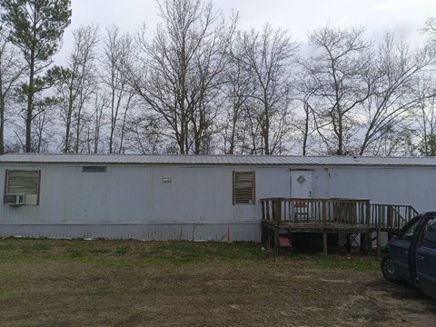 A white building with a porch and a car parked in front.