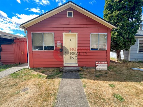 A red house with a sign that says "PROPERTY REALTY INC FOR RENT".