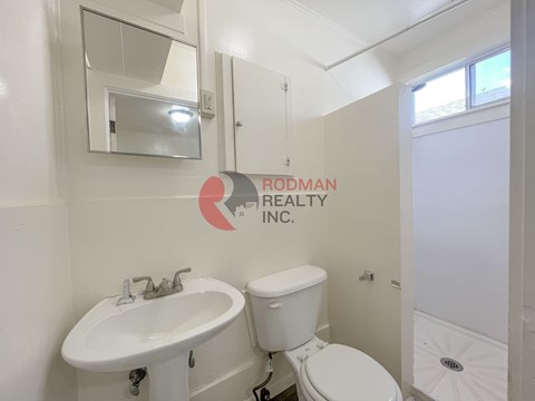 A white bathroom with a sink, toilet and a window.