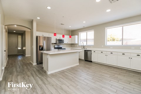 A modern kitchen with a white island and wooden flooring.