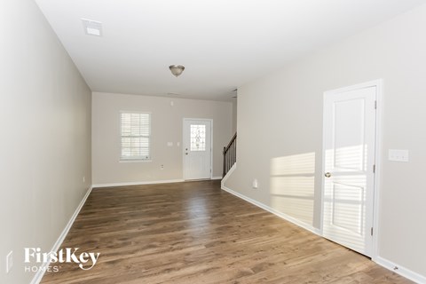 A spacious empty room with wooden floors and white walls.