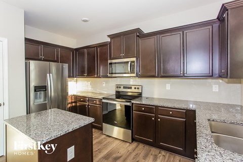 A kitchen with a granite counter top and stainless steel appliances.