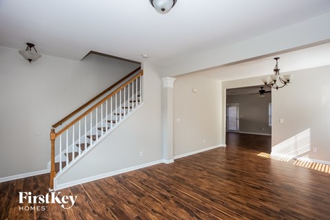 a living room with a staircase and a hard wood floor