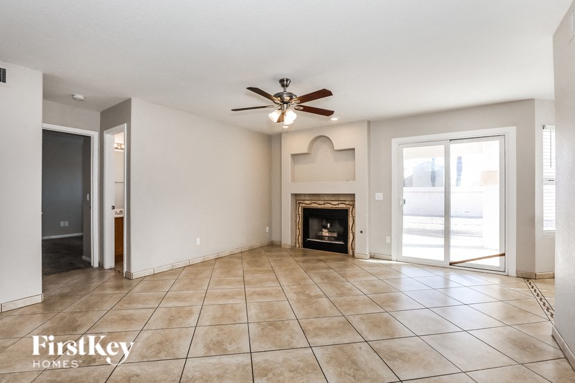 A spacious living room with a fireplace and a ceiling fan.