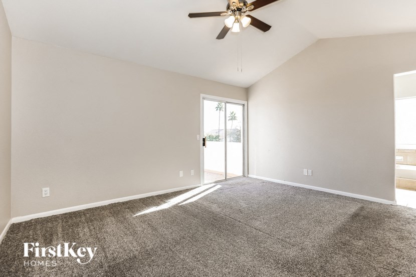 A room with a ceiling fan and a door leading to a balcony.