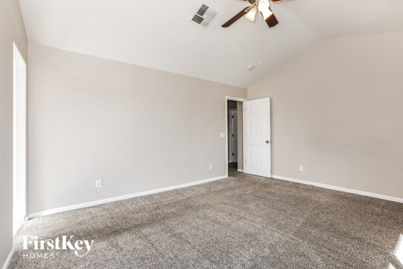 A spacious room with a ceiling fan and a door at the end.