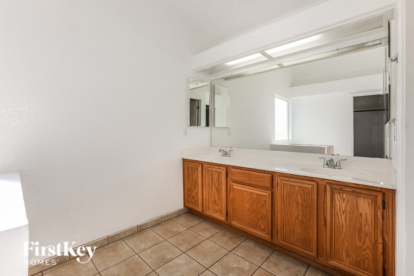 A bathroom with a white counter top and wooden cabinets.