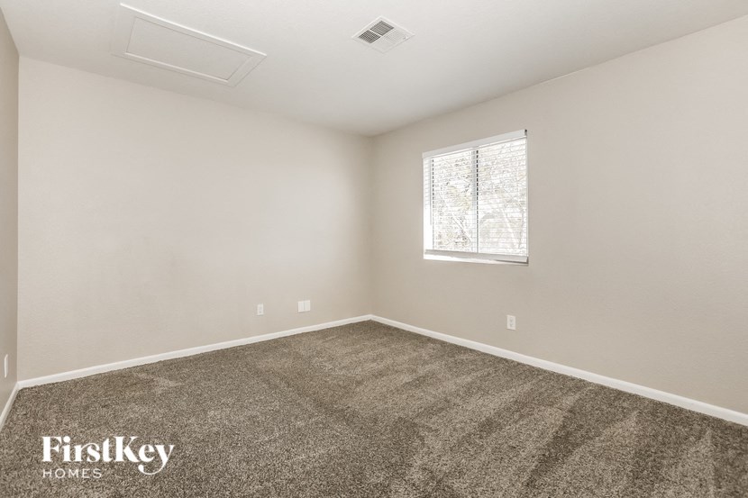 A room with a carpeted floor and a window with a white frame.