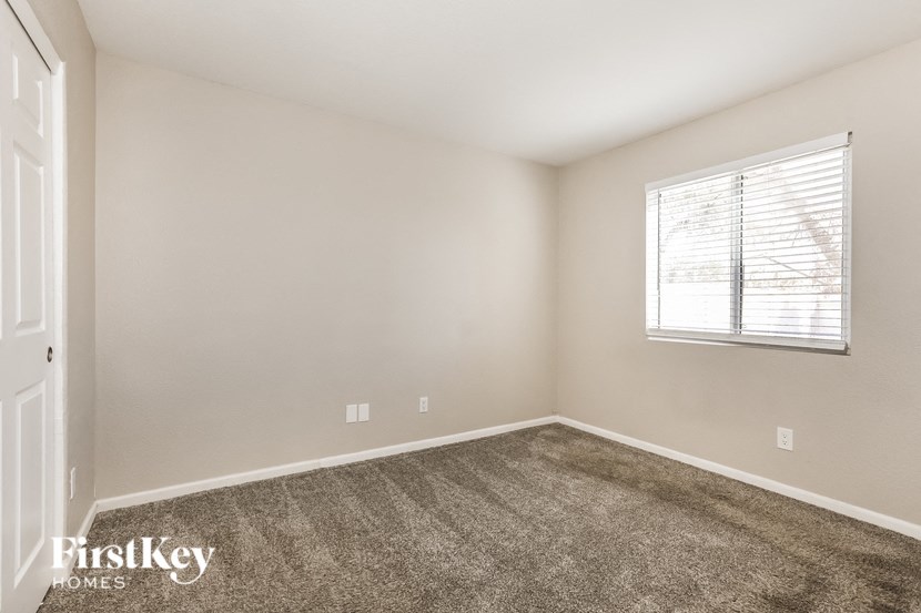A room with a carpeted floor and a window with blinds.