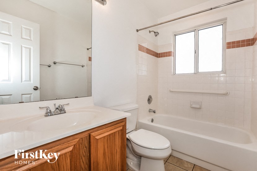 A white bathroom with a wooden cabinet and a toilet.