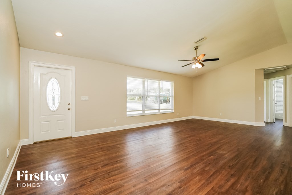 A spacious room with wooden floors and a ceiling fan.