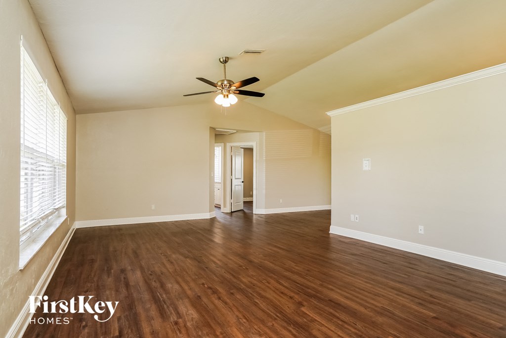 A spacious room with wooden floors and a ceiling fan.