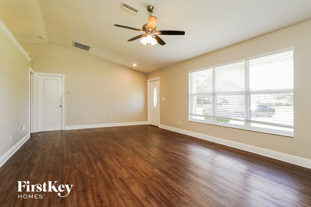 A room with a ceiling fan and wooden floors.