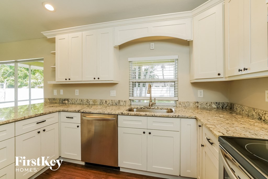 A kitchen with white cabinets and a granite countertop.