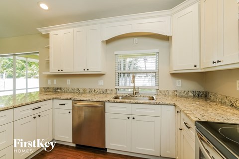 A kitchen with white cabinets and a granite countertop.