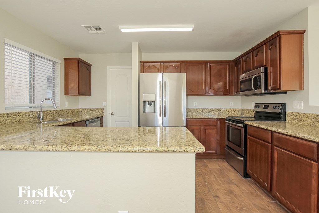 a kitchen with wooden cabinets and granite counter tops and a stainless steel refrigerator