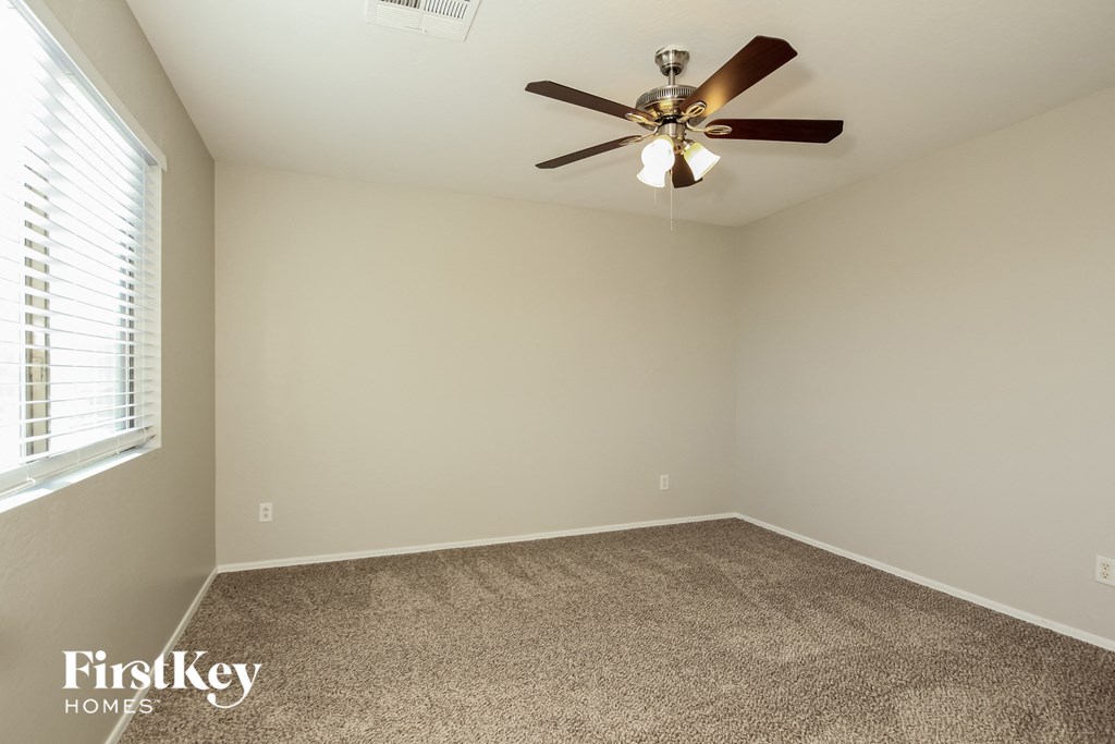 a bedroom with a ceiling fan and a carpet