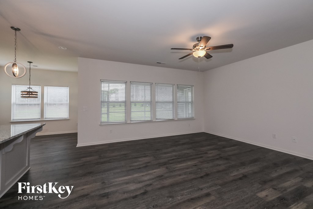 A spacious room with a ceiling fan and wooden flooring.