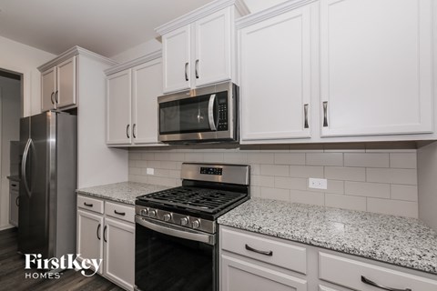A kitchen with a stove top oven and a microwave above it.