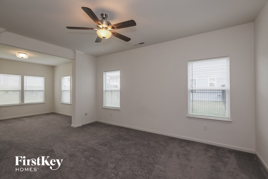 A spacious room with a ceiling fan and carpeted floor.