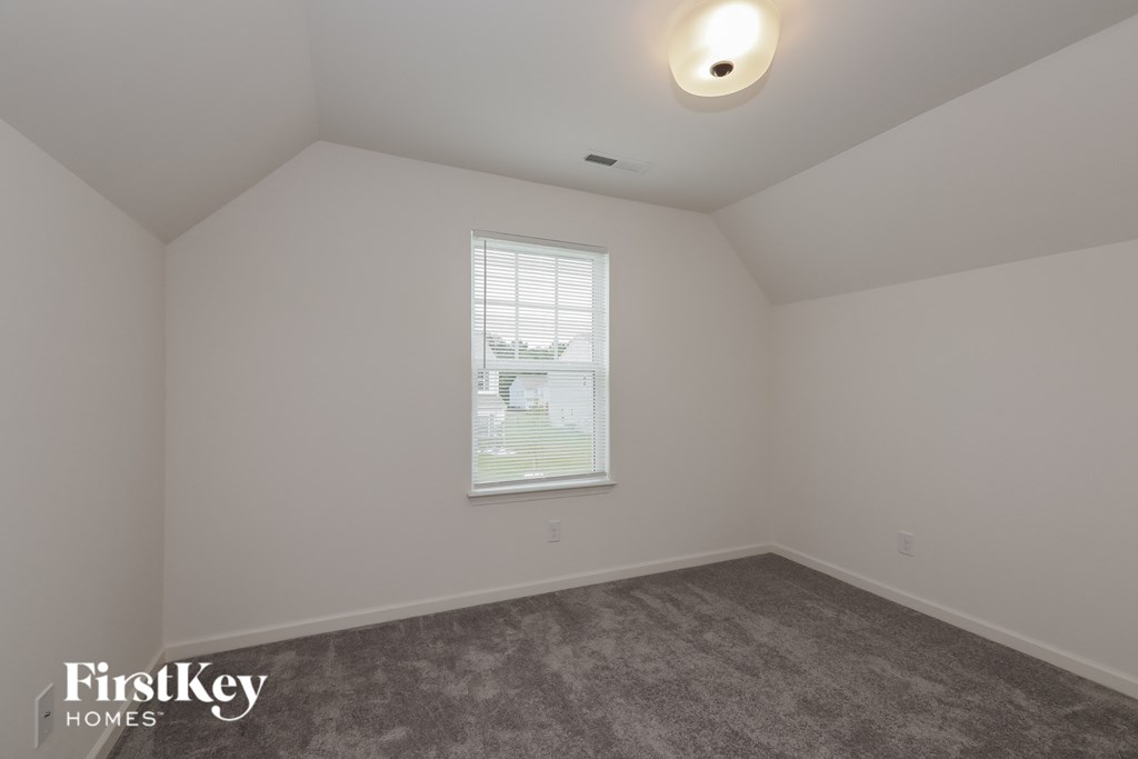 A room with a window and a carpeted floor.