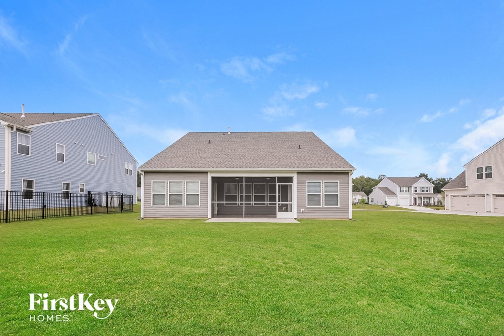 A house with a lawn in front of it and a blue sky above.