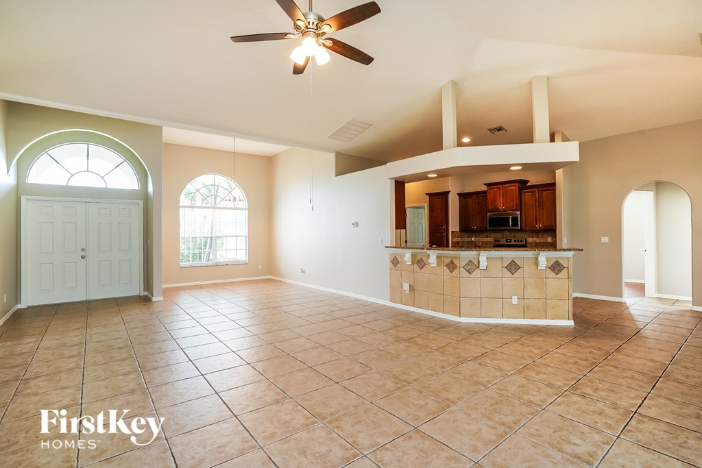 A spacious living room with a bar area and a ceiling fan.