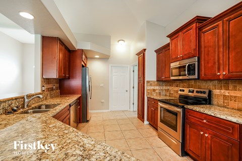 A kitchen with brown cabinets and a granite counter top.