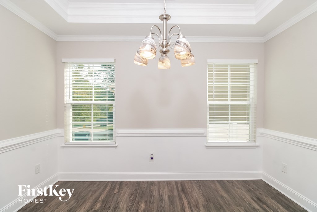 a dining room with a chandelier and two windows