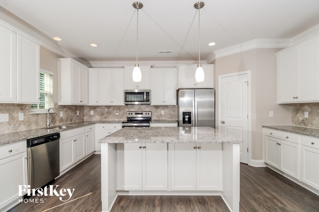 a white kitchen with marble counter tops and white cabinets