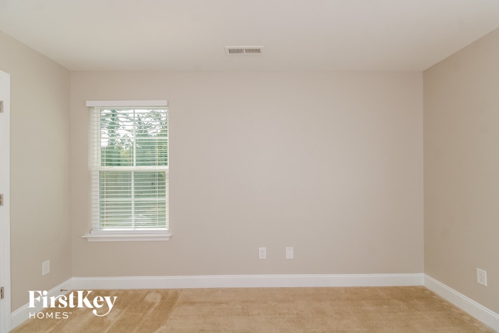 a empty room with a window and a beige wall