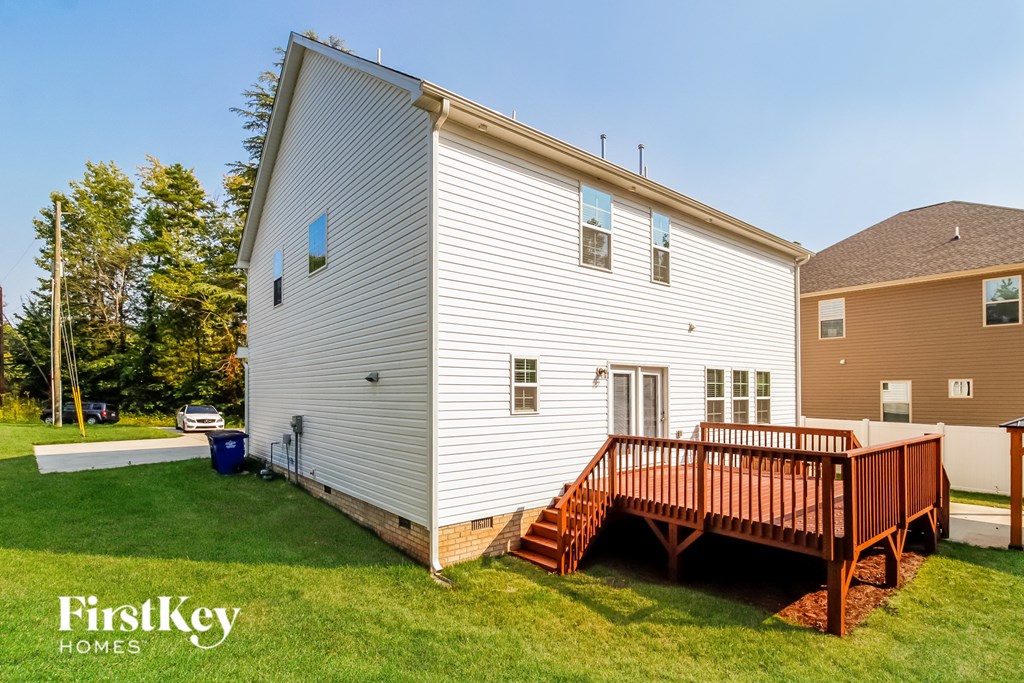 a backyard with a white house and a wooden deck