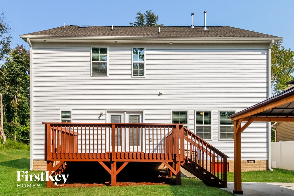 a deck with a wooden railing in front of a white house