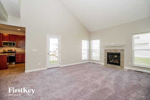 A spacious living room with a fireplace and a view of the backyard.