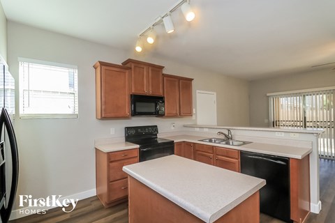 A kitchen with wooden cabinets and a black dishwasher.