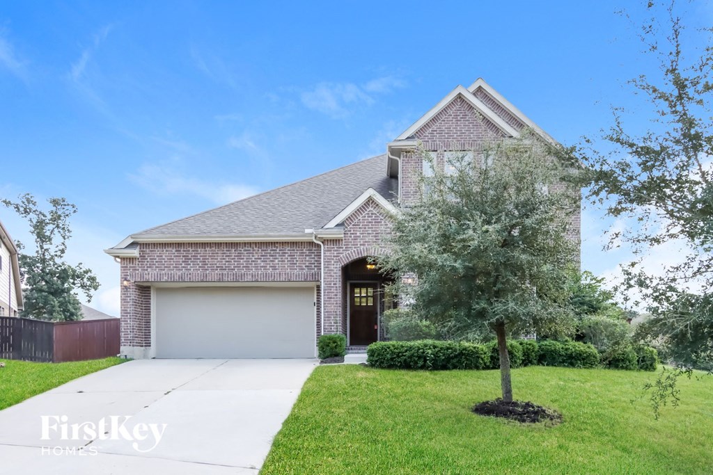 a brick house with a white garage door and a tree